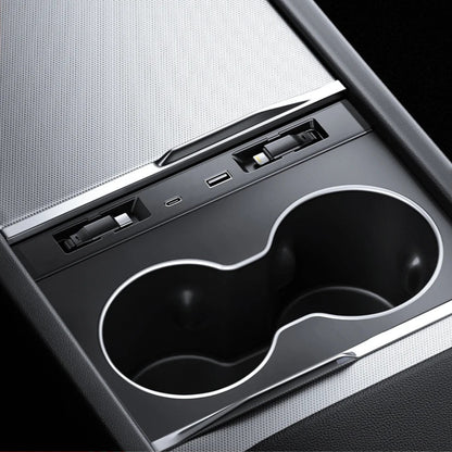 Close-up of Tesla Model 3 and Model Y center console cup holder with built-in USB charging ports and expansion dock.