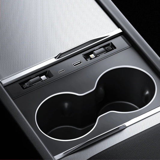 Close-up of Tesla Model 3 and Model Y center console cup holder with built-in USB charging ports and expansion dock.