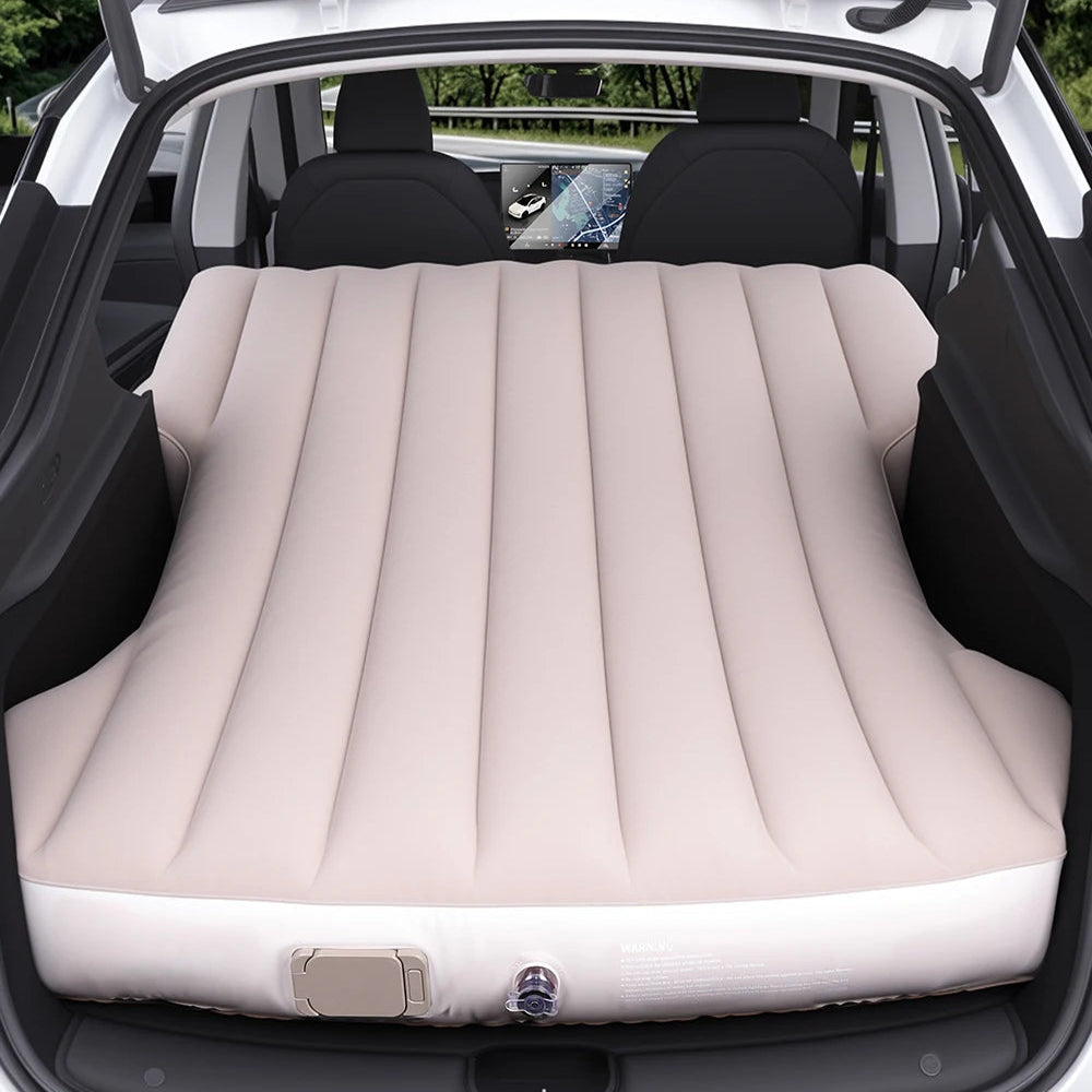 Beige inflatable camping mattress fully expanded in the rear cargo area of a Tesla Model Y, designed for car camping and road trips.