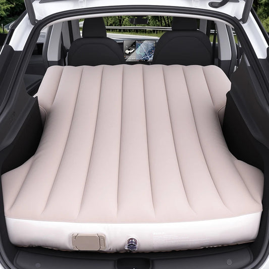 Beige inflatable camping mattress fully expanded in the rear cargo area of a Tesla Model Y, designed for car camping and road trips.